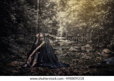 Model girl in a black dress and dark, evil queen sneaks through the stone canyon. hip toning , creative color