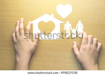 children hands with small model of house and heart and family on wooden background, concept family 