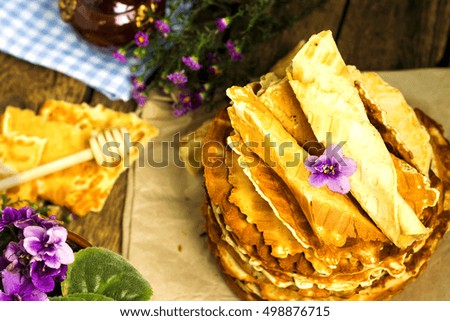 Pile of homemade wafers with flowers, earthenware teapot and book on the old wooden rusti? background