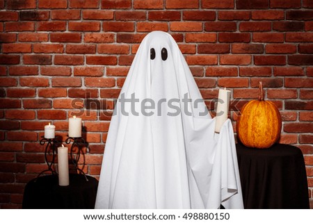 Ghost holding candle over brick background. Halloween party.
