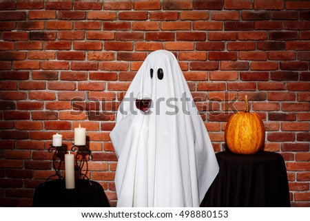 Ghost holding wine over brick background. Halloween party.