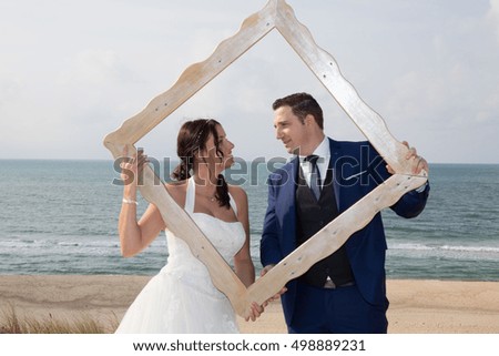 Lovely wedding couple looking through a picture frame