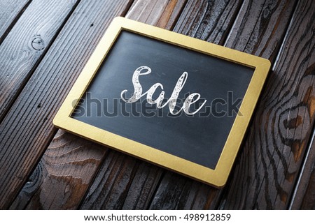 Sale Sign Written In Chalk On Chalkboard On Rustic Vintage Wood Background. Selective Focus.