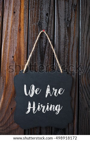 We Are Hiring Sign Written In Chalk On Chalkboard On Rustic Vintage Wood Background. Top View Selective Focus.