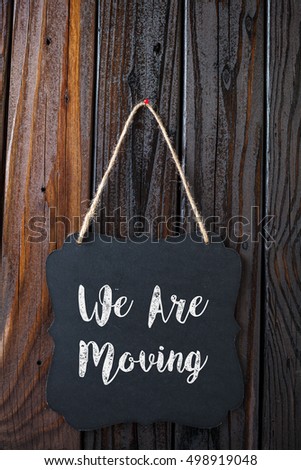We Are Moving Written In Chalk On Chalkboard On Rustic Vintage Wood Background. Top View Selective Focus.
