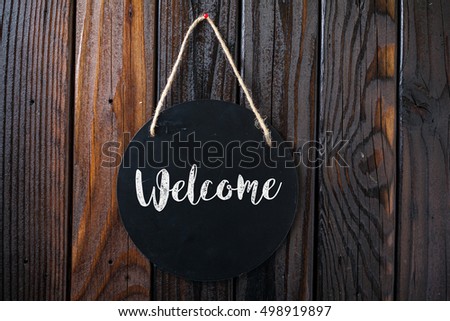 Welcome Sign Written In Chalk On Chalkboard On Rustic Vintage Wood Background. Top View Selective Focus.
