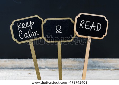 Keep Calm and Read message written with chalk on mini blackboard labels, defocused chalkboard and wooden table in background. Fun and humor concept