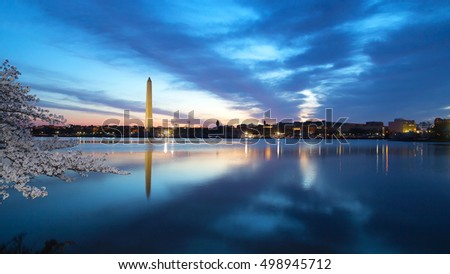 Washington Monument at night with the city skyline and cherry blossom. Colorful reflections of Washington landmarks in the Tidal Basin.