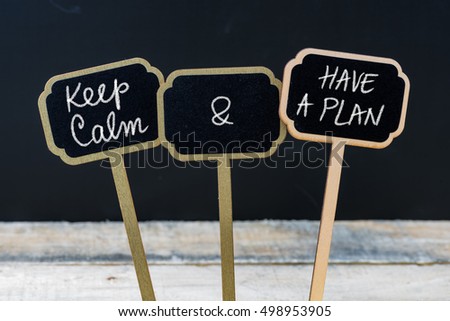 Keep Calm and Have A Plan message written with chalk on mini blackboard labels, defocused chalkboard and wooden table in background. Fun and humor concept