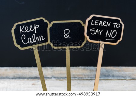 Keep Calm and Learn To Say NO message written with chalk on mini blackboard labels, defocused chalkboard and wooden table in background. Fun and humor concept