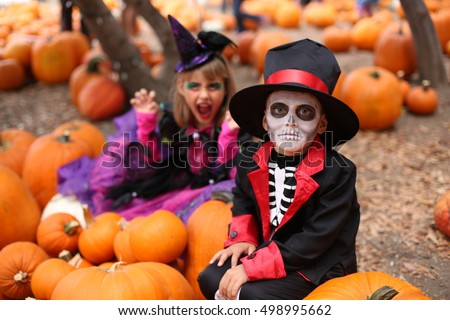 Trick or treat. Boy in a Halloween costume of skeleton with hat and smocking between orange pumpkins. Halloween kids with halloween costumes