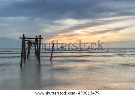 Golden Hour moment,beautiful tropical sunset background, wooden water pump tower on the muddy beach. cloudy and yellow sky.surface level shot.low tide sea view
