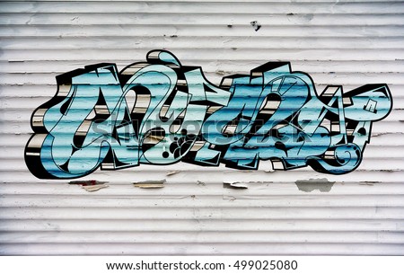 Street art of graffiti painted with spray paint on a roller shutter.. Urban contemporary culture. Abstract color creative drawing. Word gust