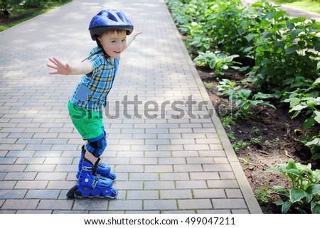 Little boy in helmet roller skates as bird in garden at summer day