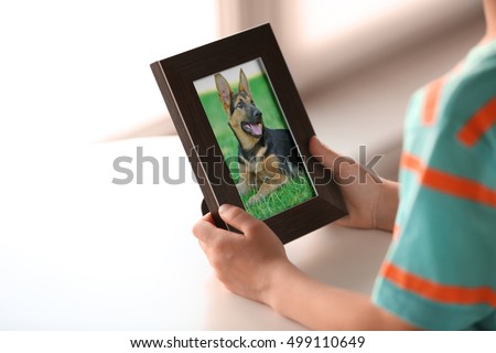 Little boy holding photo frame with picture of dog. Happy memories concept.