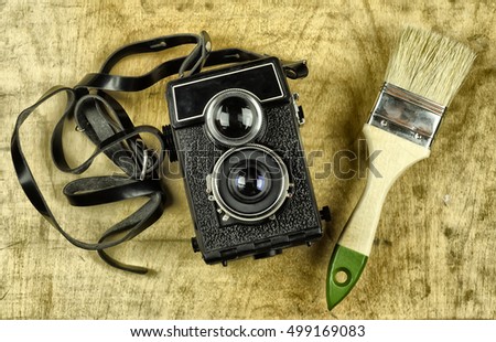 The old analog photo camera and brush in color