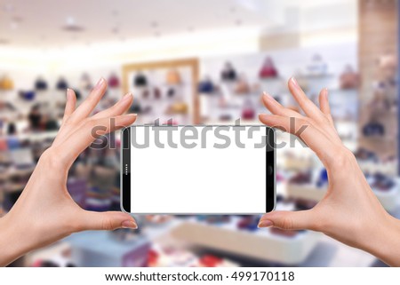female holding a smartphone isolated blank screen with two hands on Abstract blur department store, urban lifestyle concept, shoe store, shopping blur background, ready for snap a picture