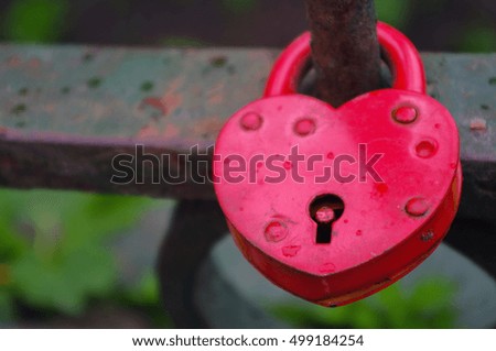 Red Padlock in heart style on the fence of a bridge