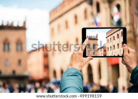 Person uses a tablet to take a picture in the old city of Bologna, Emilia Romagna region, Italy.