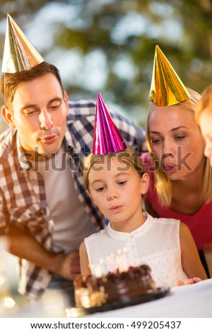 Family celebrating daughter birthday and blowing cake candles
