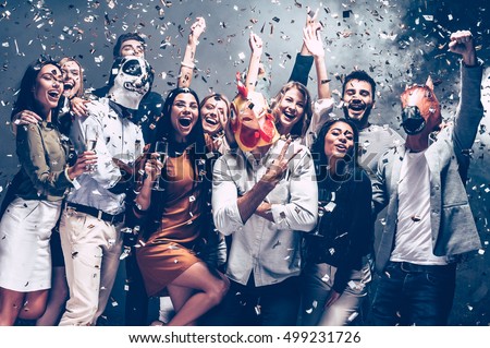 Year of rooster. Group of young people in animal masks throwing confetti and looking happy  Royalty-Free Stock Photo #499231726