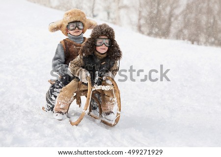 Two boys sledding with mountain warm winter day