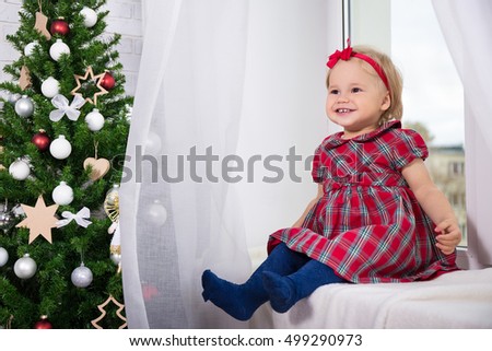 Christmas and family concept - cute little girl and decorated Christmas tree