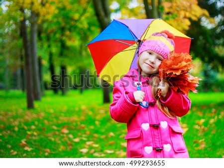 happy girl with a colorful umbrella in he autumn park
