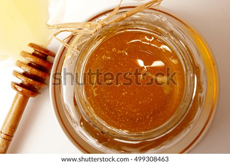 Glass jar of sweet delicious honey and dipper in spread honey on white background