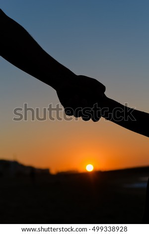 Back side view silhouettes of father holding his child hand over sunset background. Book cover idea design