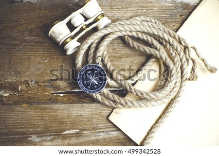 Compass, binoculars and rope on wood