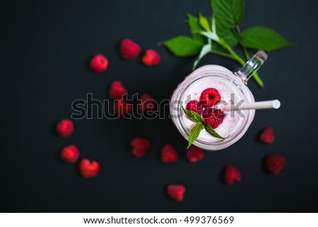 Pink raspberry smoothie in a mason jar with straws on a black background