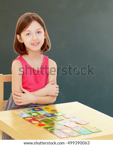 Intelligent little girl demonstrates how she folded cards with drawings on the table.During a lesson in school.