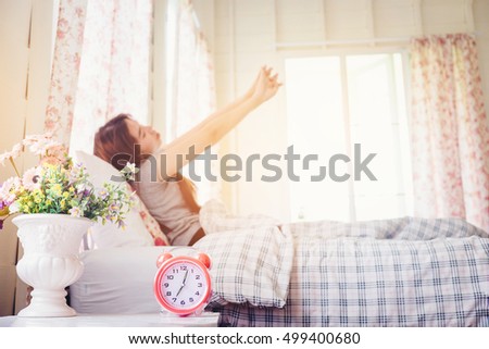 young woman wake up stretch on the bed in the morning alarm clock look so fresh day (vintage tone) Royalty-Free Stock Photo #499400680