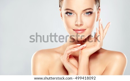 Beautiful Young Woman with Clean Fresh Skin  touch own face . Facial  treatment   . Cosmetology , beauty  and spa . Royalty-Free Stock Photo #499418092