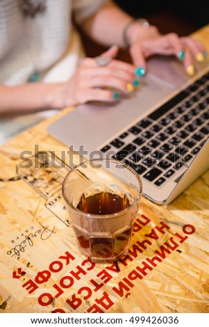 Russian girl is drinking coffee in a cafe with a laptop