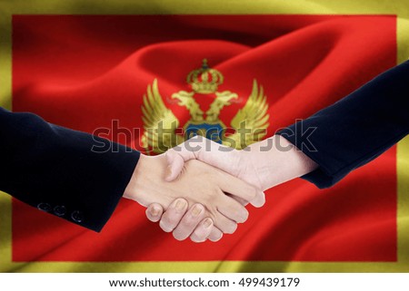 Picture of two businesspeople hands, closing a deal and shaking hands with Montenegro flag background