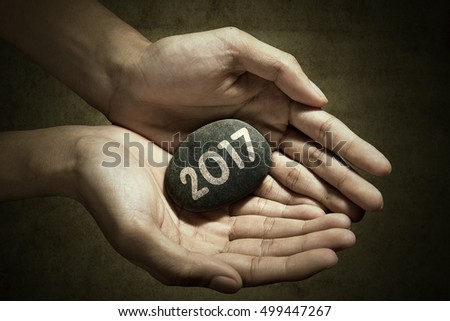 Concept of New Year 2017. Picture of hand holding a stone pebble with number 2017