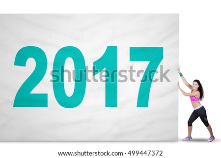 Concept of Happy New Year 2017. Picture of a fit woman wearing sportswear and pulling a big flag with number 2017