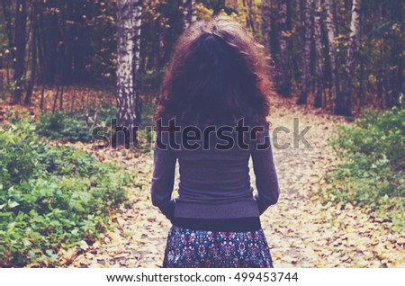 Girl with curly dark hair into the autumn wood
