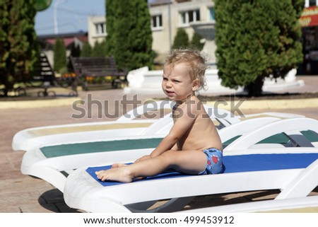 Child resting on recliner at aquapark in summer