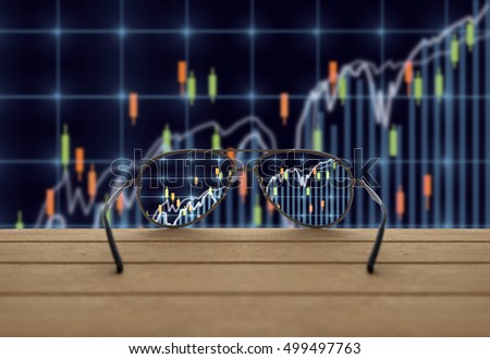 Stock exchange market trading graph focused in glasses lenses on the wooden over the abstract photo blurred of trading graph background, business technology trading concept