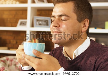 Young man enjoying with closed eyes drink coffee, tea or chocolate. Handsome man enjoying a break drinking a cup of coffee.