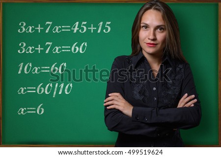 Beautiful young girl (teacher, schoolgirl, student or business woman) posing near a school blackboard with mathematical tasks