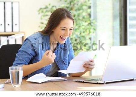 Excited casual entrepreneur girl reading good news in a letter in a desktop at office Royalty-Free Stock Photo #499576018