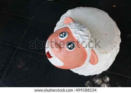 a white sheep doll in back blackground, sheep doll seat in garden, decorate in park,
child seat