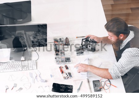 Man constructing drone, double exposure, free space. Top view on technician workplace with special tools. Toy repair shop. electronic development concept