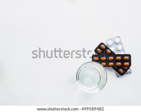 Top view of water glass and medicine on white background for treat fever with copy space