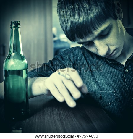 Toned Photo of Tired Young Man sleep with Bottle of the Beer and Cigarette