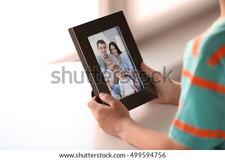 Little boy holding photo frame with picture of family. Happy memories concept.